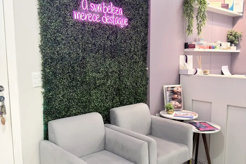 Recepção lavanda com poltronas cinza e parede verde com letreiro neon