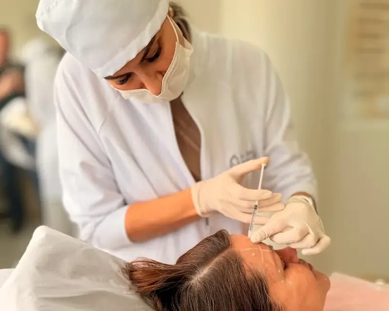 Profissional aplicando um procedimento facial em paciente deitada
