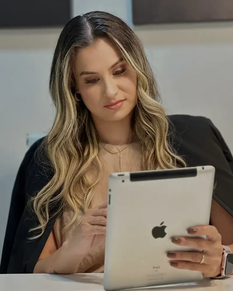 Dra. Jamile Varnier olhando o tablet, sentada à mesa